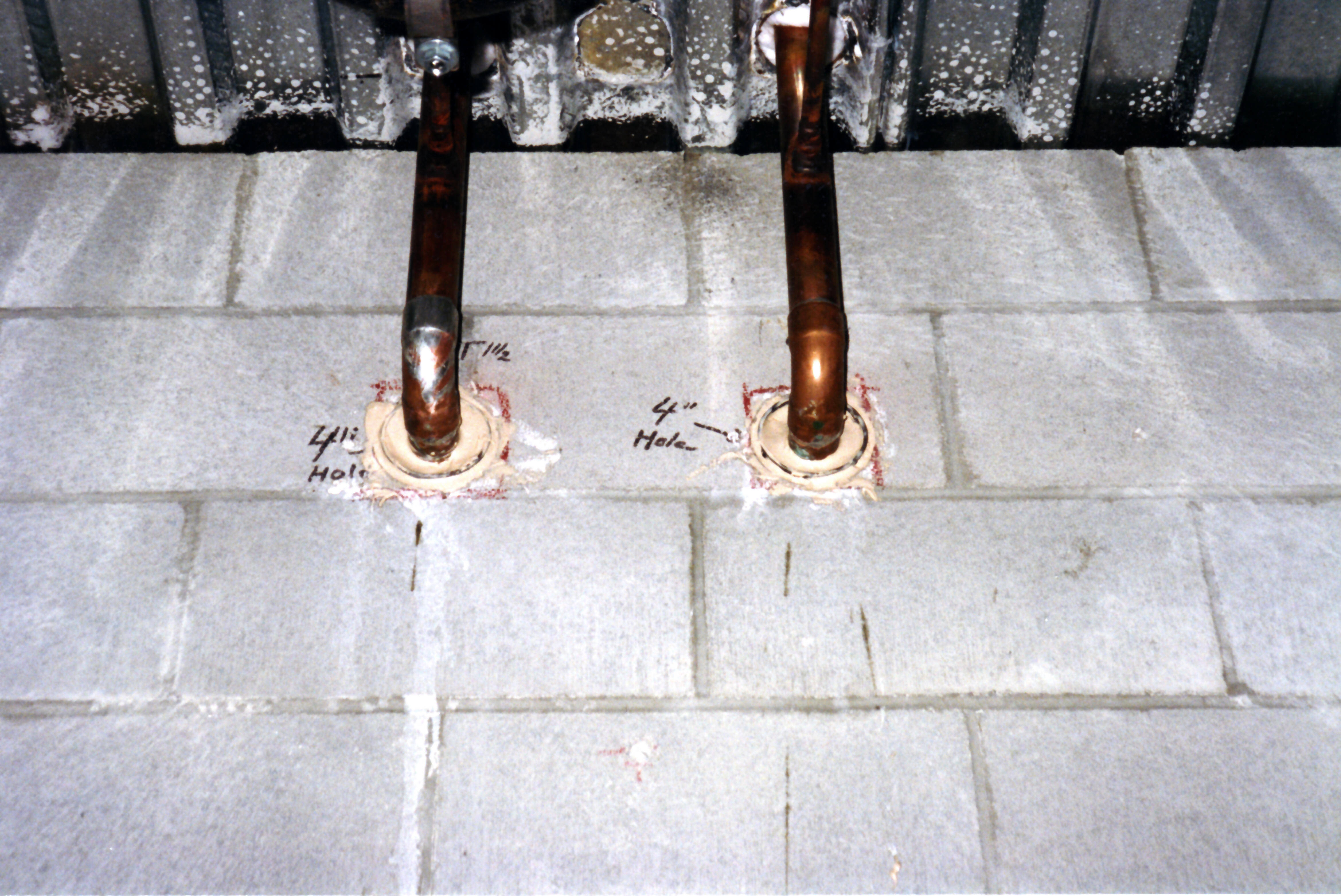 Fire stopping around two copper pipes passing through a concrete block wall