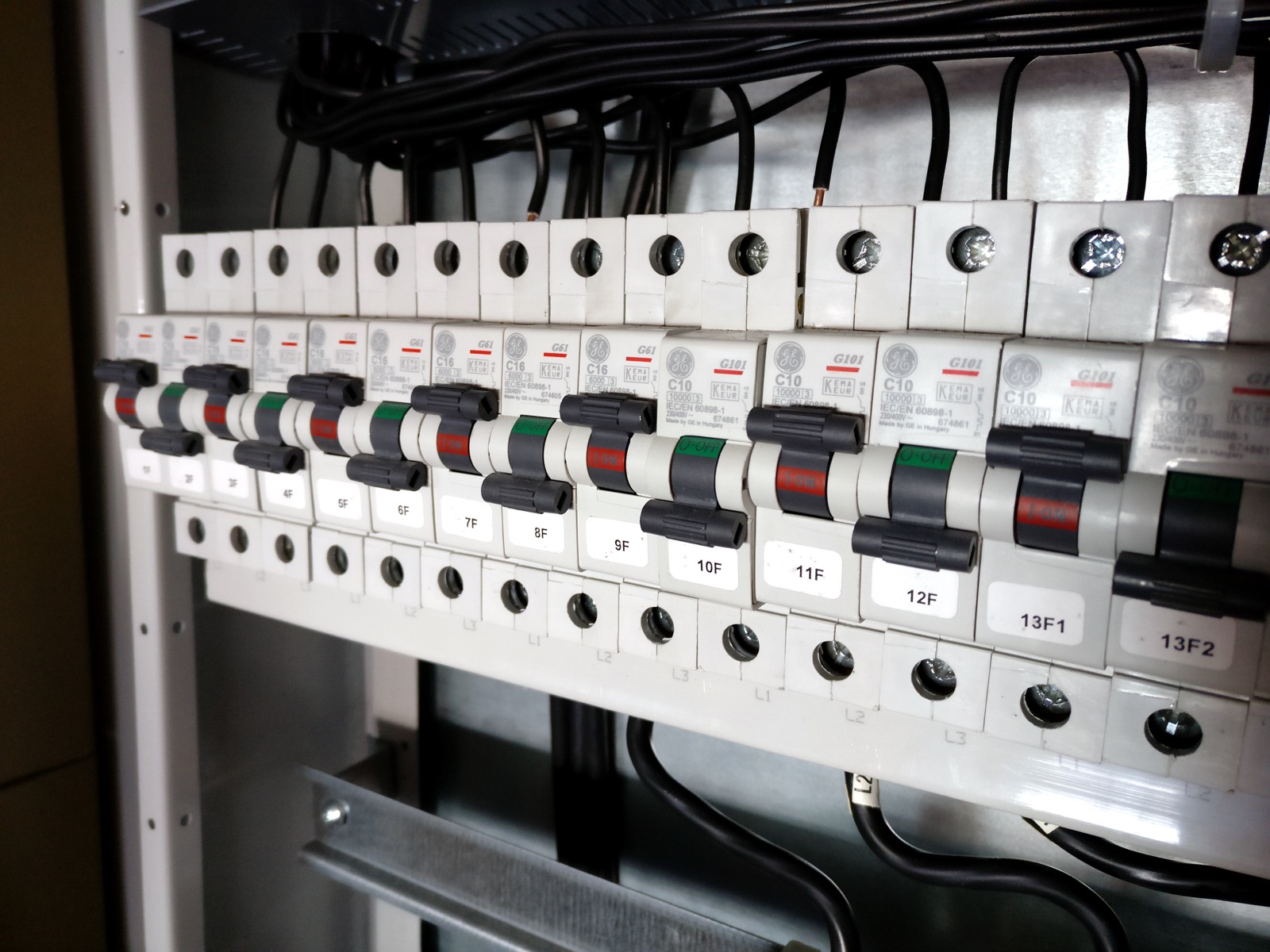 Row of labelled miniature circuit breakers mounted on a DIN rail inside an open electrical distribution board