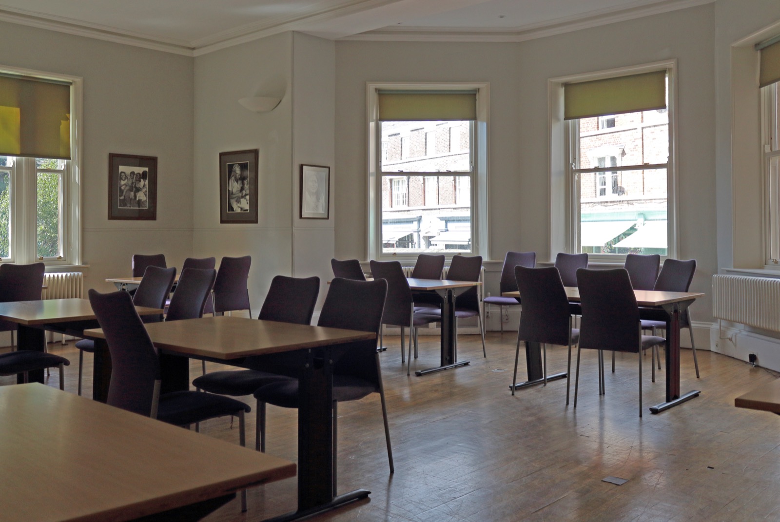 Empty classroom with rows of tables and chairs and tall sash windows